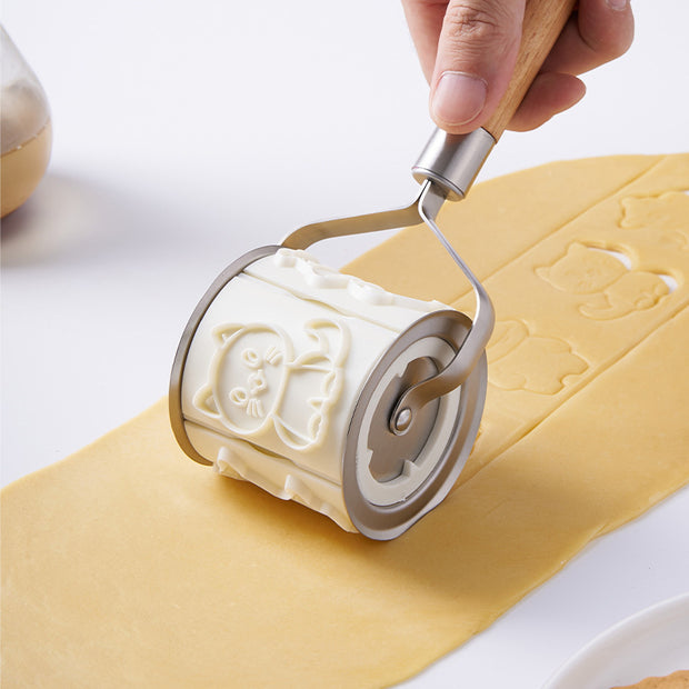 Hand using a roller bucket cartoon animal biscuit mold on dough for baking in the kitchen.