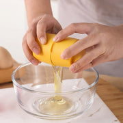 hands using an egg cracker to separate egg into a bowl, kitchen baking tool, egg cracker for mess-free cooking